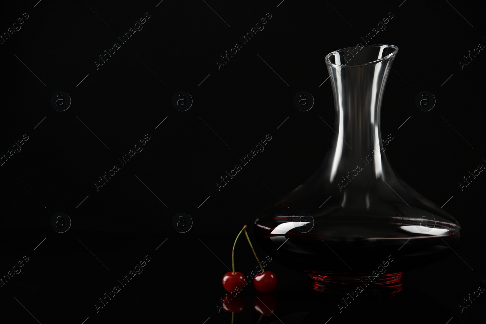 Photo of Delicious cherry wine and ripe juicy berries on black background. Space for text