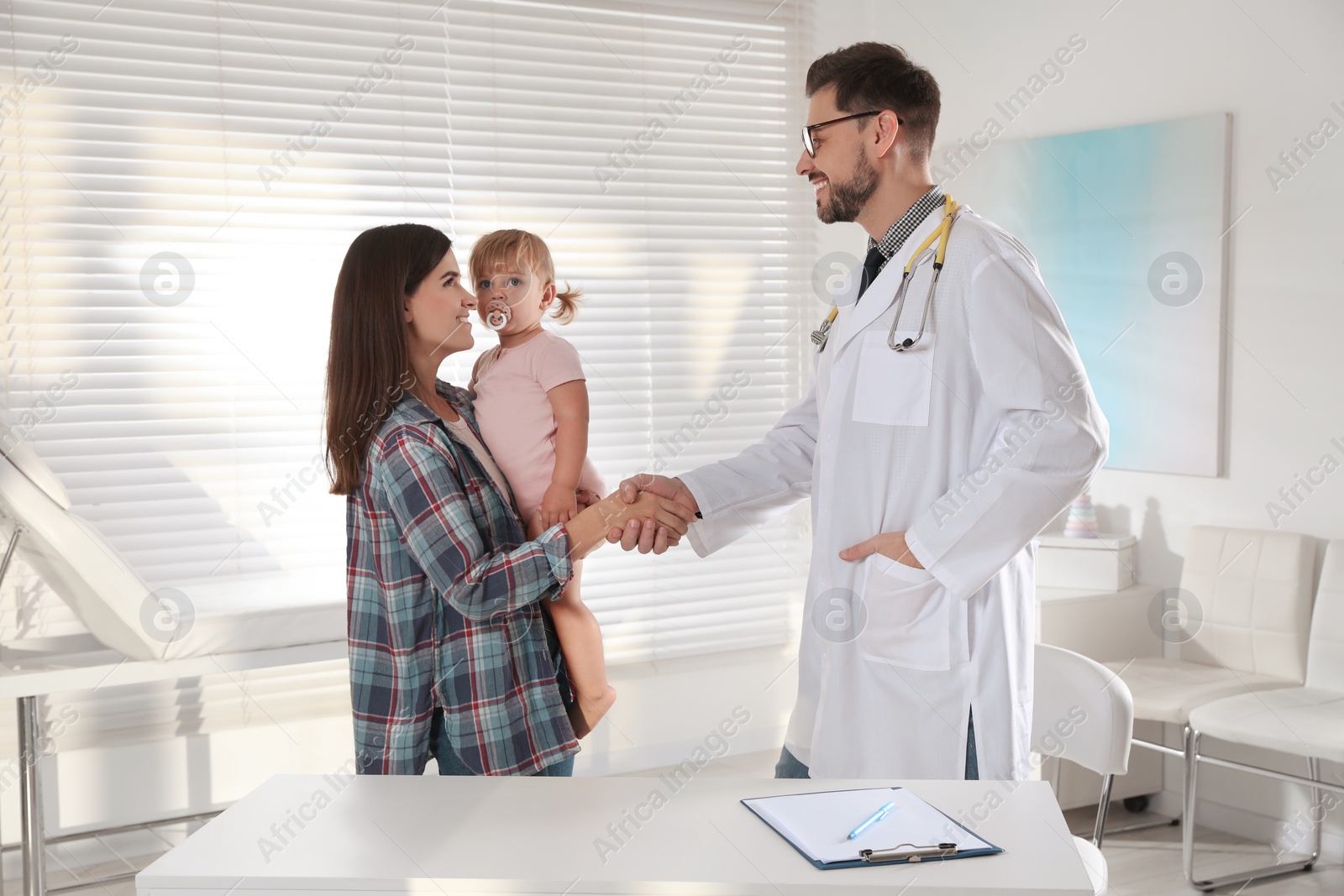 Photo of Mother and her cute baby having appointment with pediatrician in clinic. Doctor examining little girl