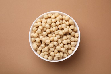 Photo of Tasty cereal balls in bowl on brown table, top view