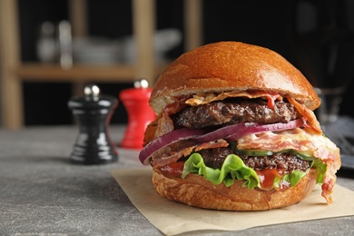 Photo of Tasty burger with bacon and lettuce on table. Space for text