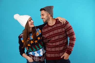 Photo of Couple wearing Christmas sweaters and hats on blue background