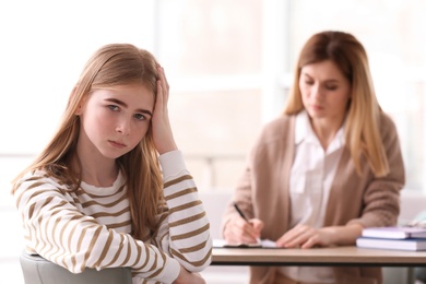 Young female psychologist working with teenage girl in office