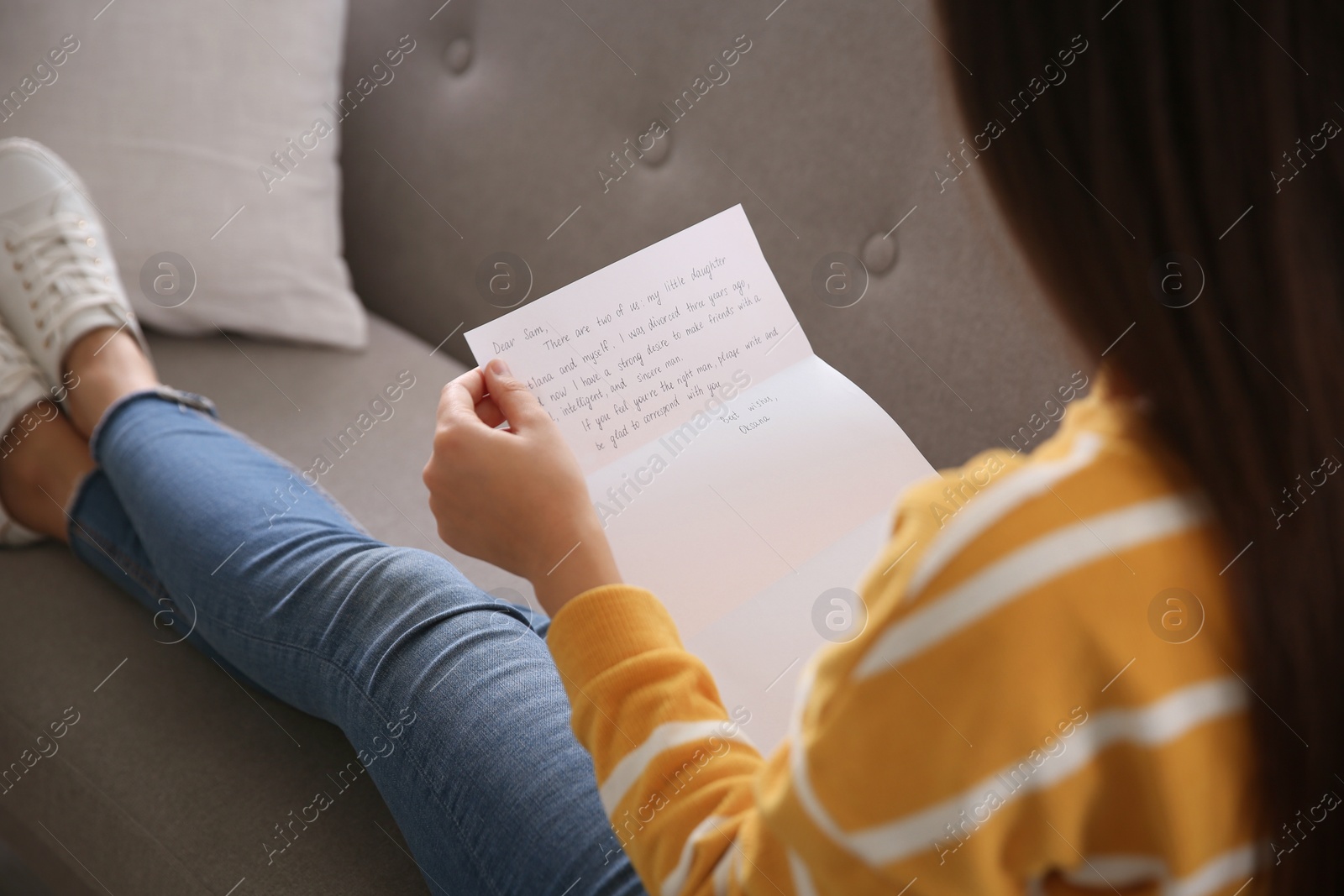 Photo of Woman reading letter on sofa at home, closeup