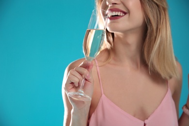 Beautiful woman with glass of champagne on color background, closeup. Space for text