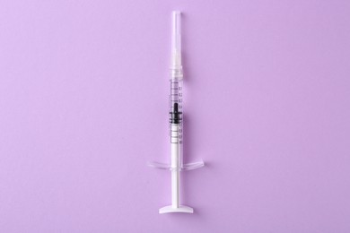 Cosmetology. One medical syringe on violet background, top view