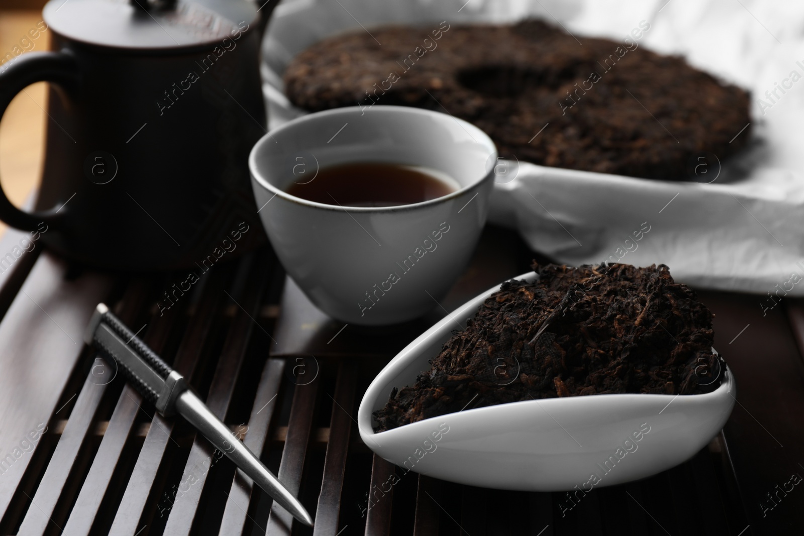 Photo of Aromatic pu-erh and knife on wooden tray, closeup. Fermented tea