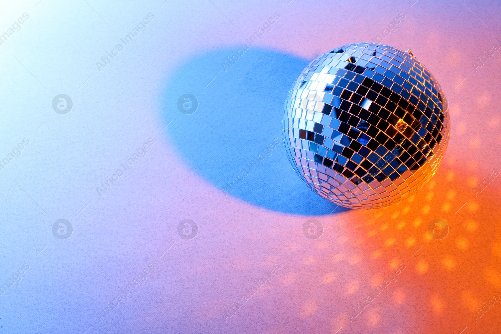 Photo of Bright shiny disco ball on color background. Space for text