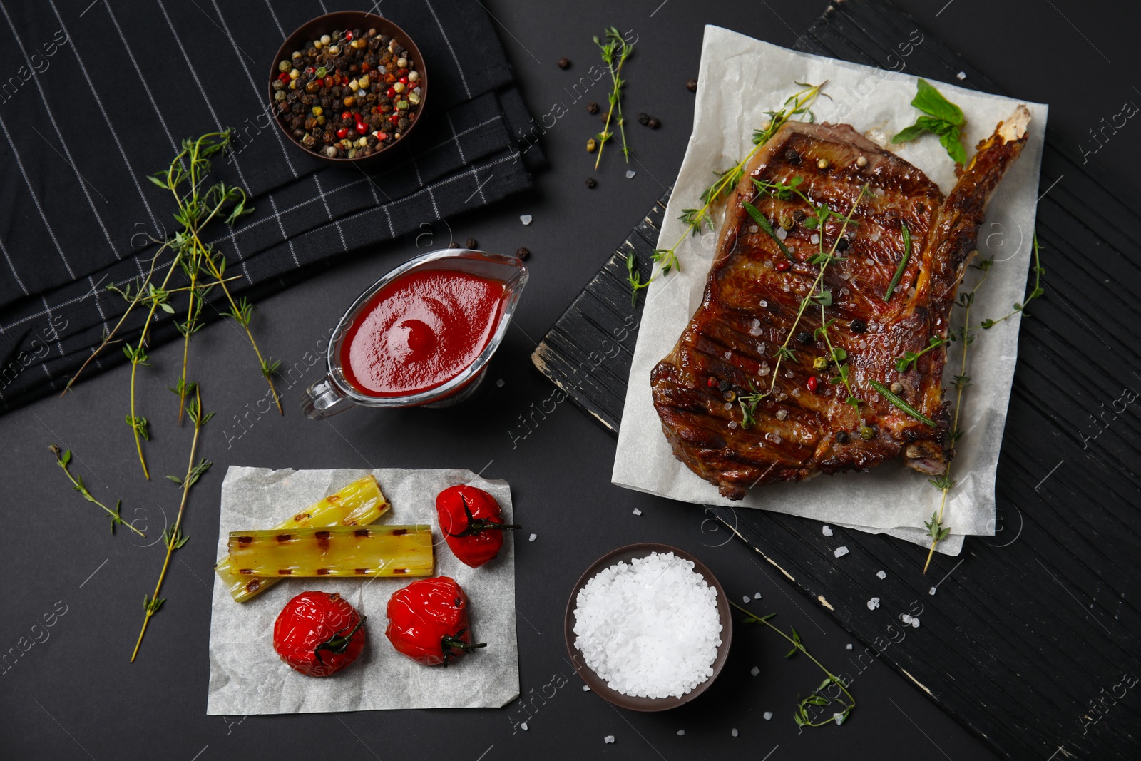 Photo of Flat lay composition with grilled meat on black background