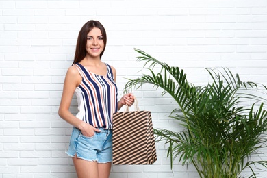 Portrait of young woman with paper bags near white brick wall