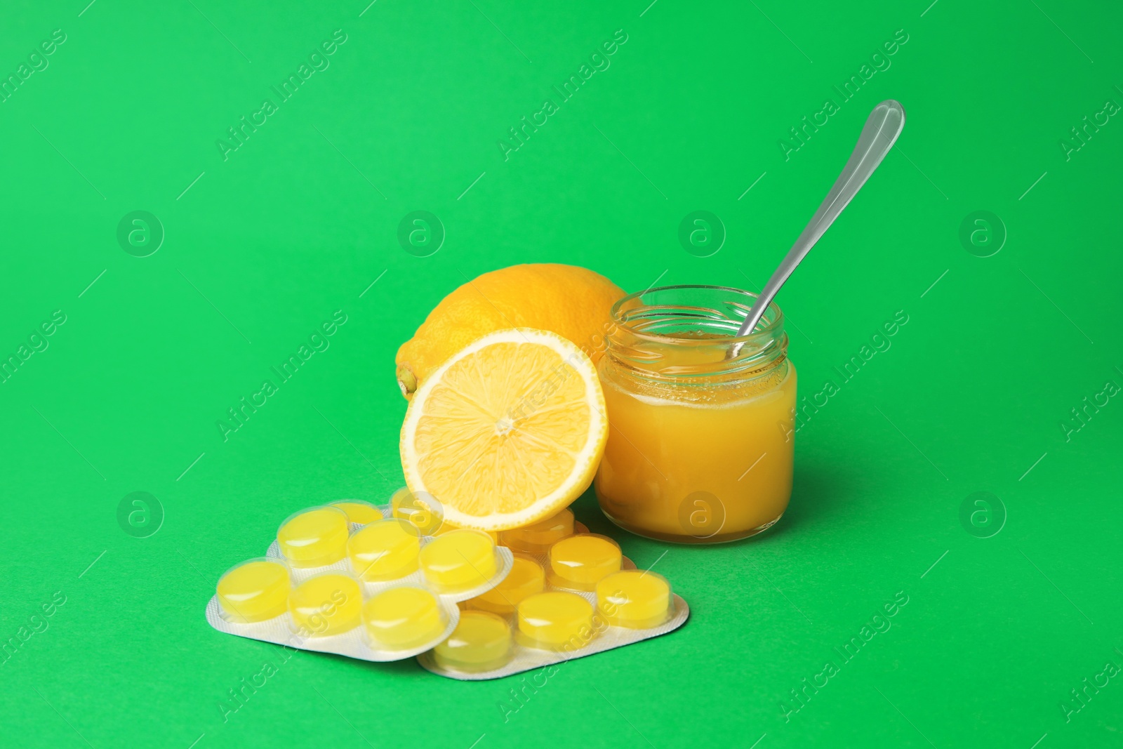 Photo of Cough drops, fresh lemons and honey on green background
