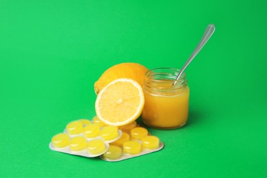 Photo of Cough drops, fresh lemons and honey on green background