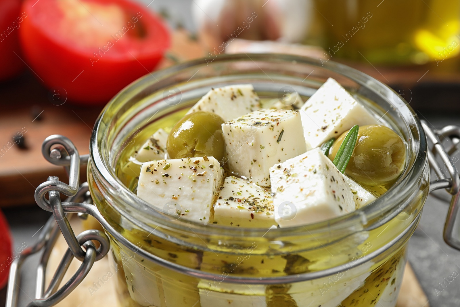 Photo of Pickled feta cheese in jar on grey table, closeup