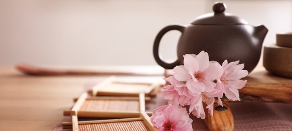 Image of Pot, sakura flowers and bamboo coasters for traditional tea ceremony on table. Banner design