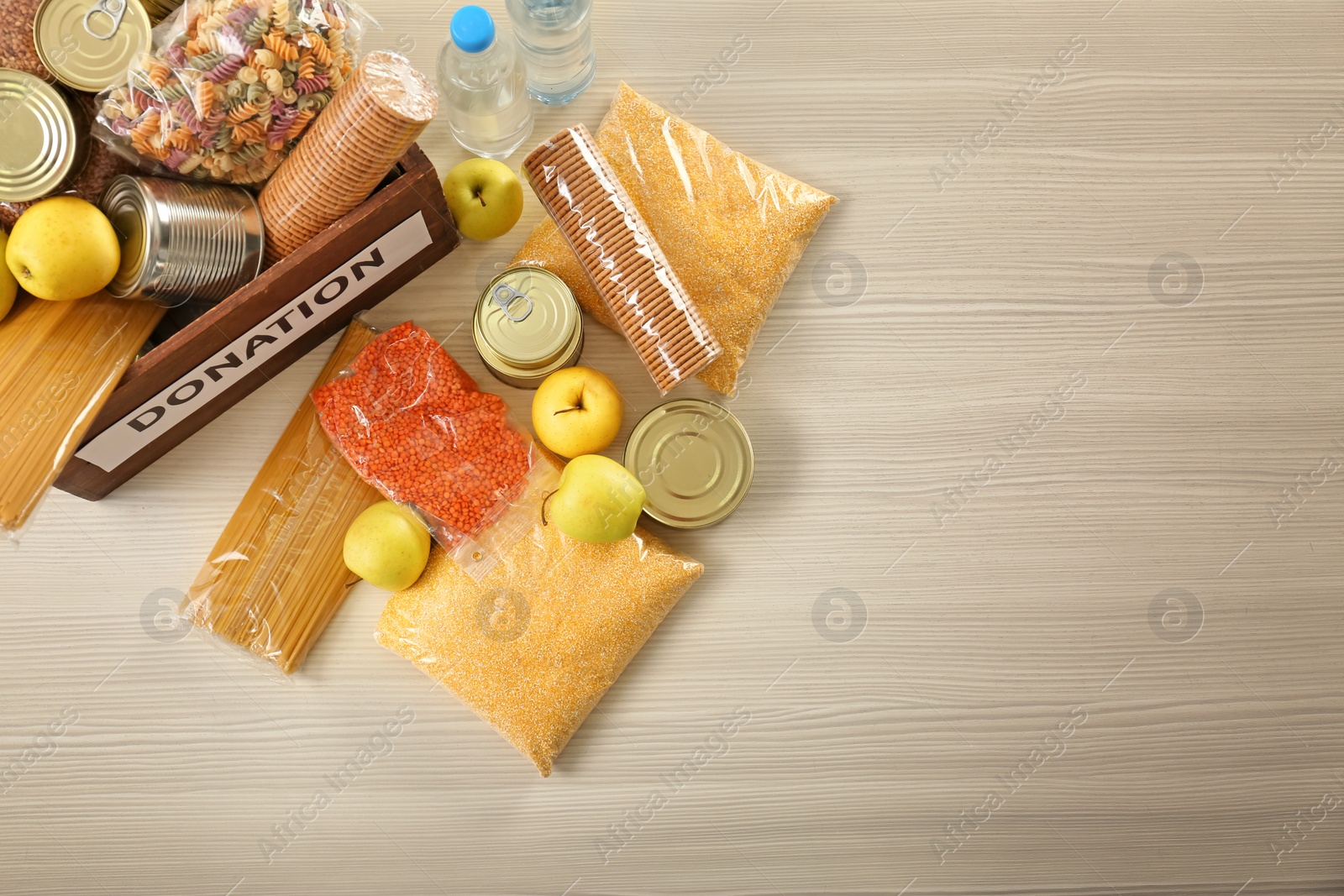 Photo of Donation box and different products on wooden table, top view. Space for text