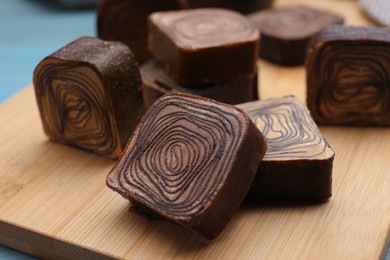 Photo of Tasty chocolate candies on wooden board, closeup