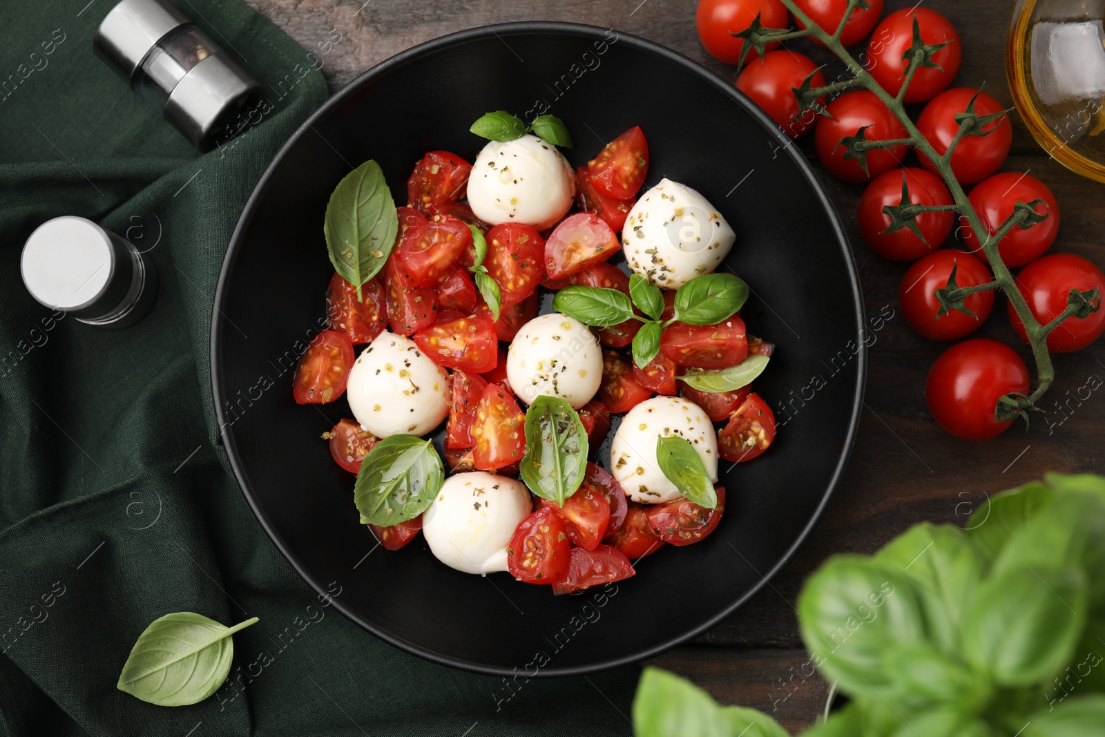 Photo of Tasty salad Caprese with tomatoes, mozzarella balls and basil on wooden table, flat lay