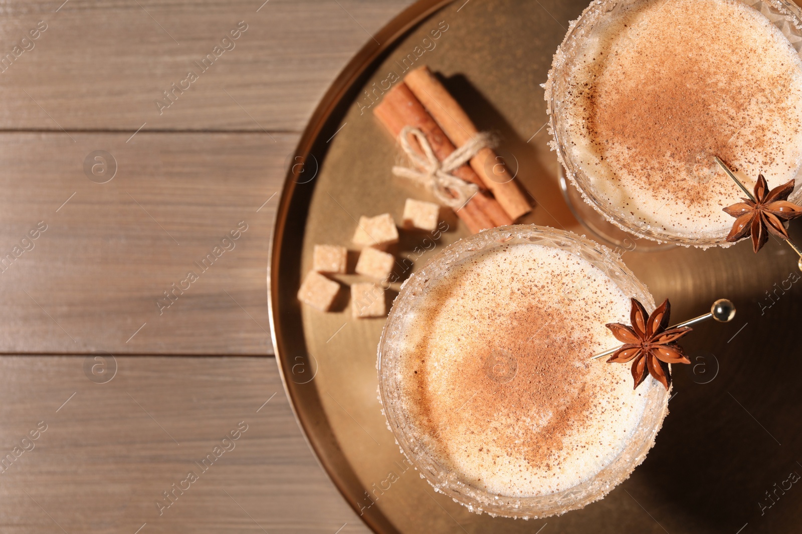 Photo of Delicious eggnog with cinnamon and anise on wooden table, flat lay. Space for text