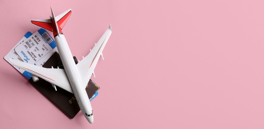 Photo of Toy airplane and passport with tickets on pink background, flat lay. Space for text