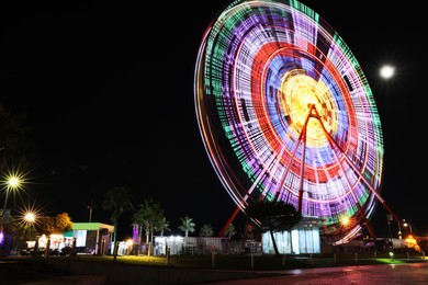 Beautiful glowing Ferris wheel against dark sky, space for text
