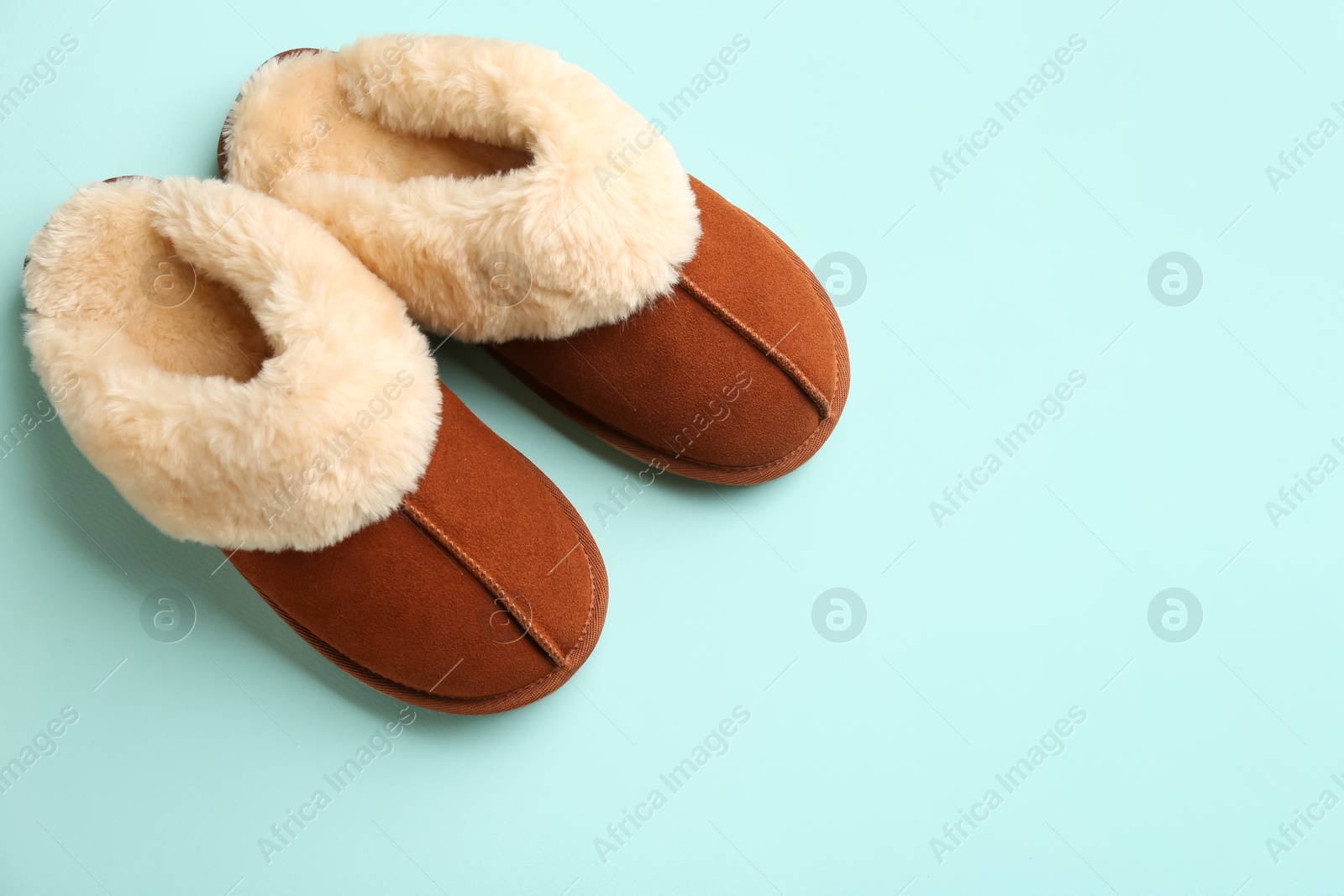 Photo of Pair of stylish soft slippers on turquoise background, flat lay. Space for text