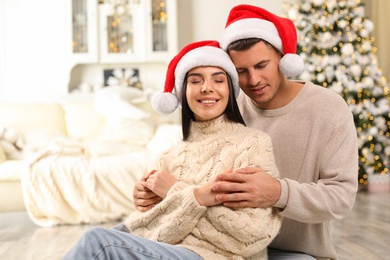 Photo of Happy couple in Santa hats at home. Christmas celebration