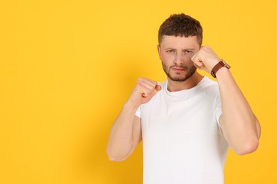 Photo of Young man ready to fight on orange background, space for text