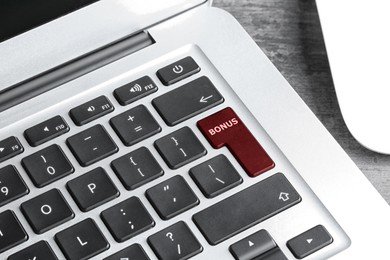 Image of Dark red button with word Bonus on laptop keyboard, closeup