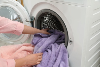 Woman taking towels out of washing machine in laundry room