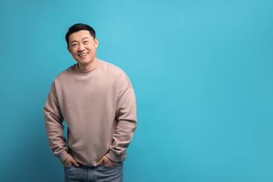 Portrait of happy man on light blue background. Space for text