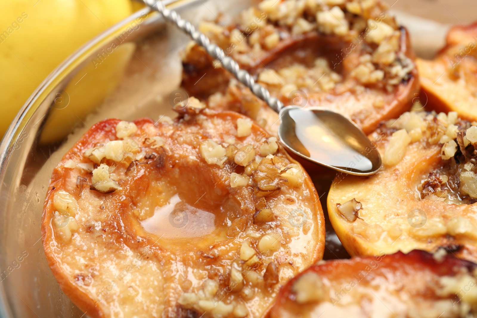 Photo of Tasty baked quinces with walnuts and honey in bowl on table, closeup