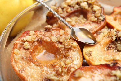 Photo of Tasty baked quinces with walnuts and honey in bowl on table, closeup