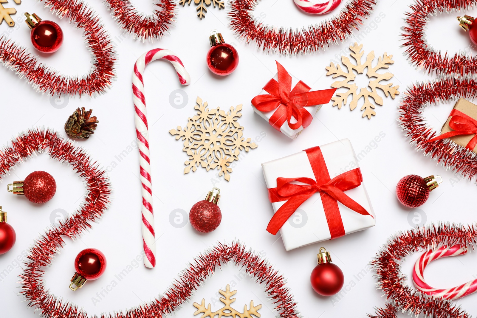 Photo of Red tinsel and Christmas decor on white background, flat lay