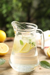 Photo of Glass jug of cold lemonade on wooden table