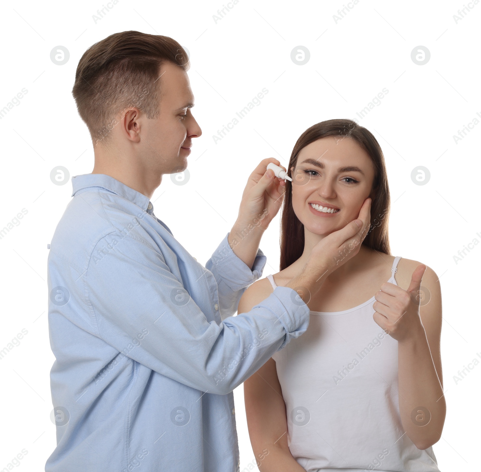 Photo of Man dripping medication into woman's ear on white background