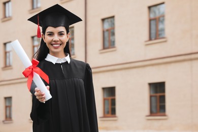 Photo of Happy student with diploma after graduation ceremony outdoors. Space for text