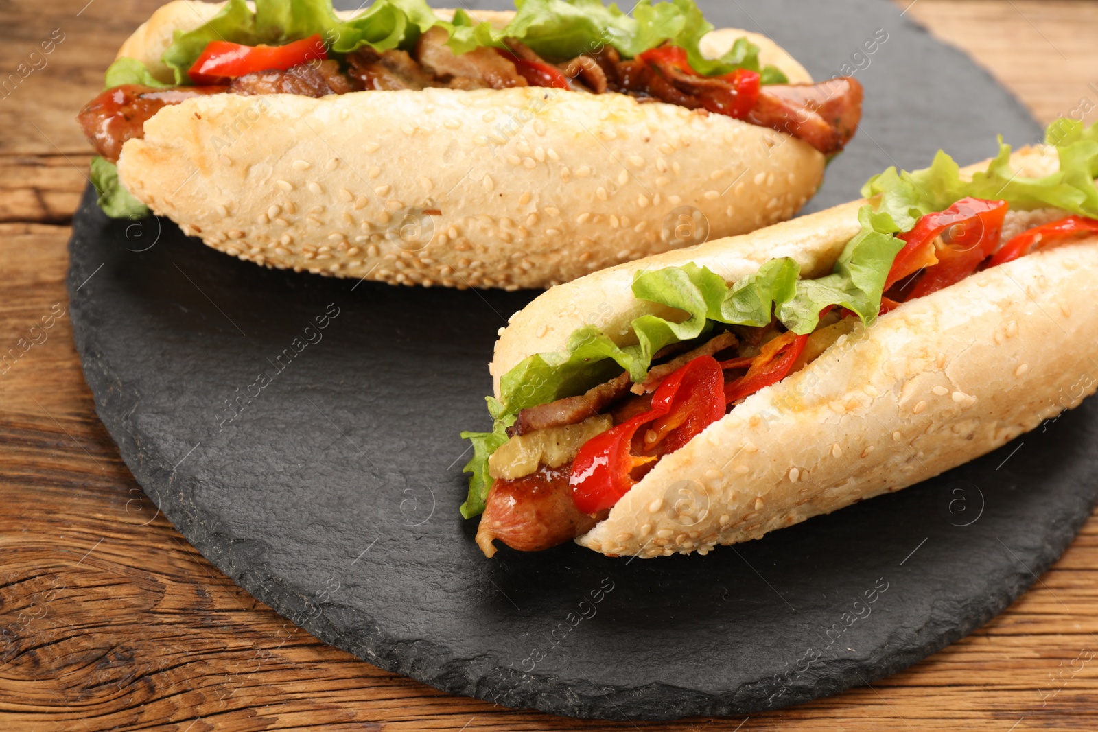 Photo of Tasty hot dogs on wooden table, closeup. Fast food