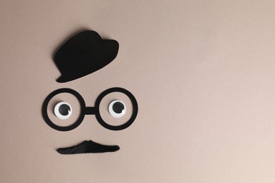 Photo of Man's face made of fake mustache, paper hat and glasses on grey background, top view. Space for text