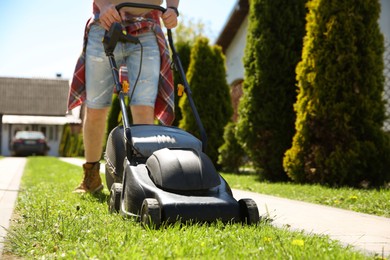 Man cutting green grass with lawn mower on backyard, closeup