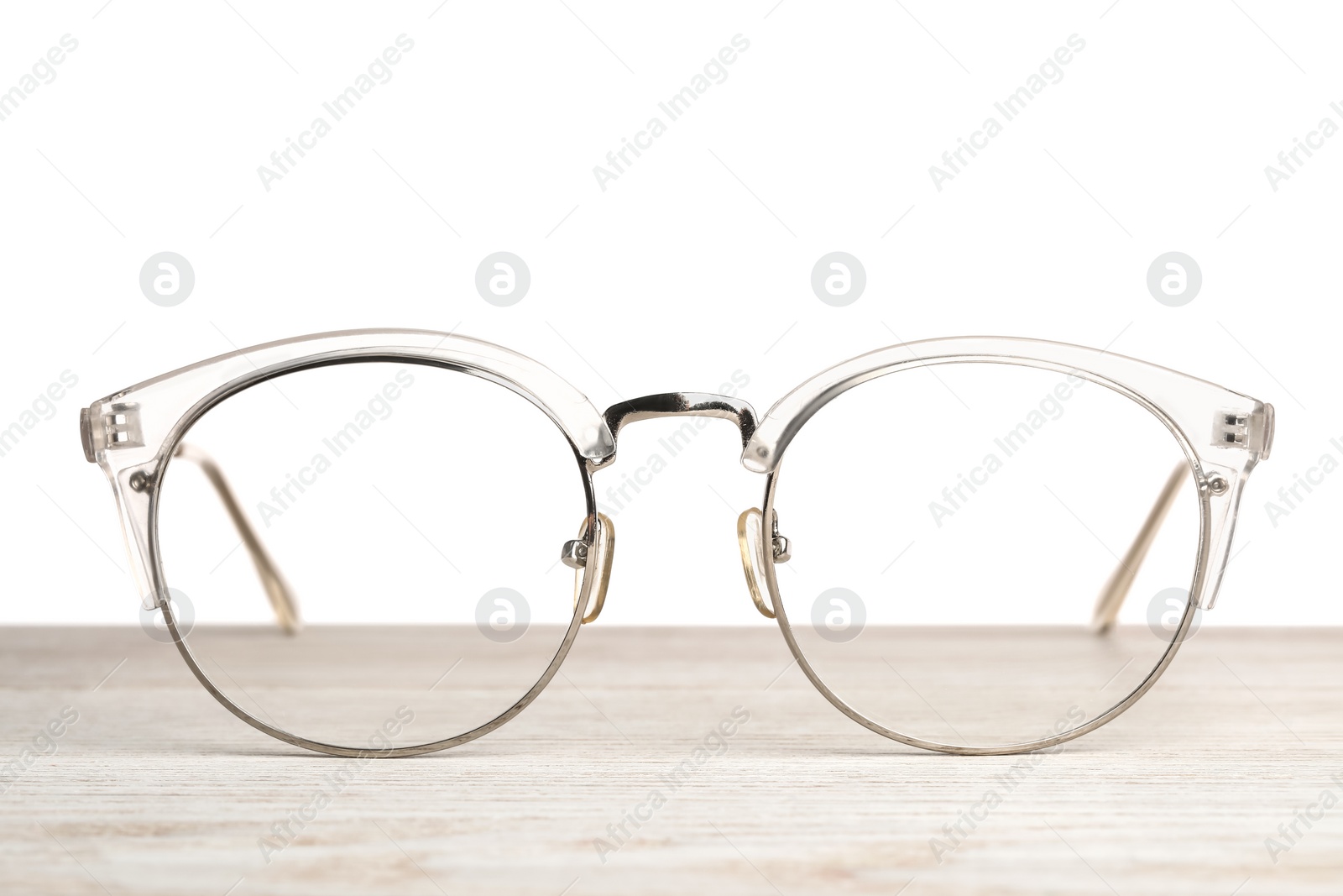 Photo of Stylish glasses on wooden table against white background