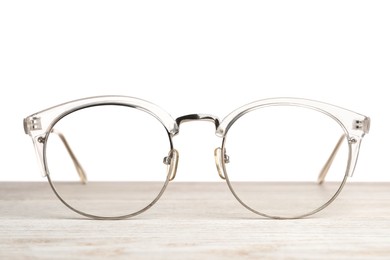 Stylish glasses on wooden table against white background