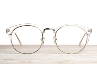 Photo of Stylish glasses on wooden table against white background