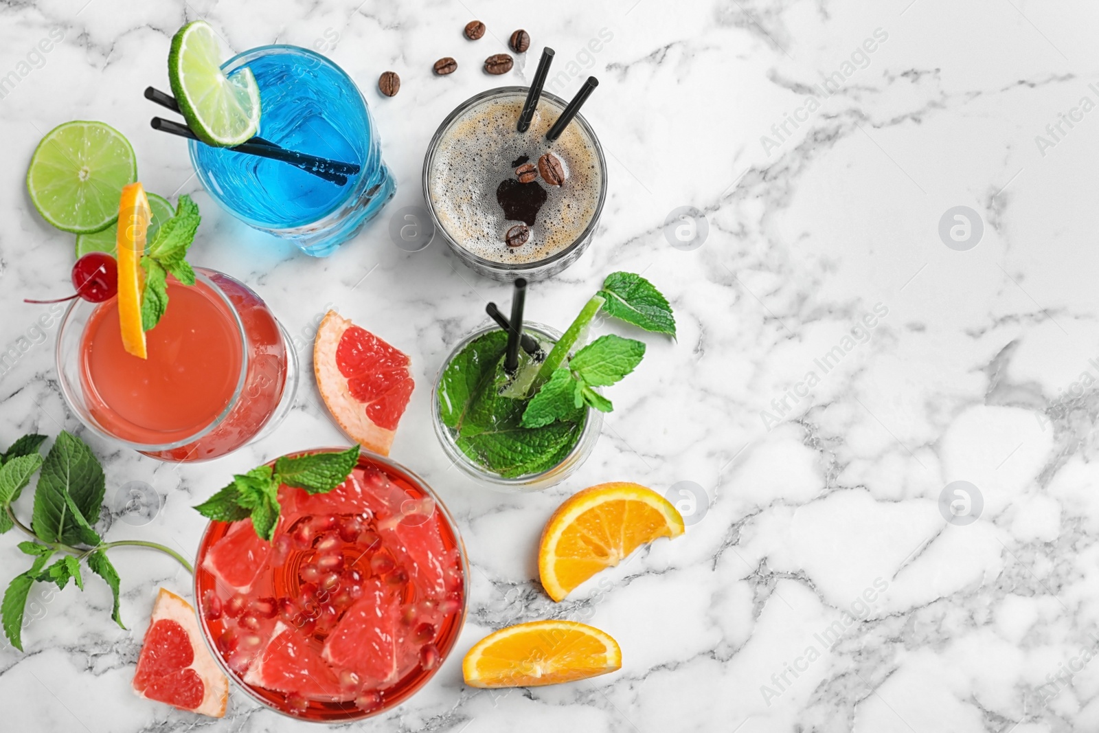 Photo of Flat lay composition with glasses of different tasty refreshing cocktails on marble background. Space for text