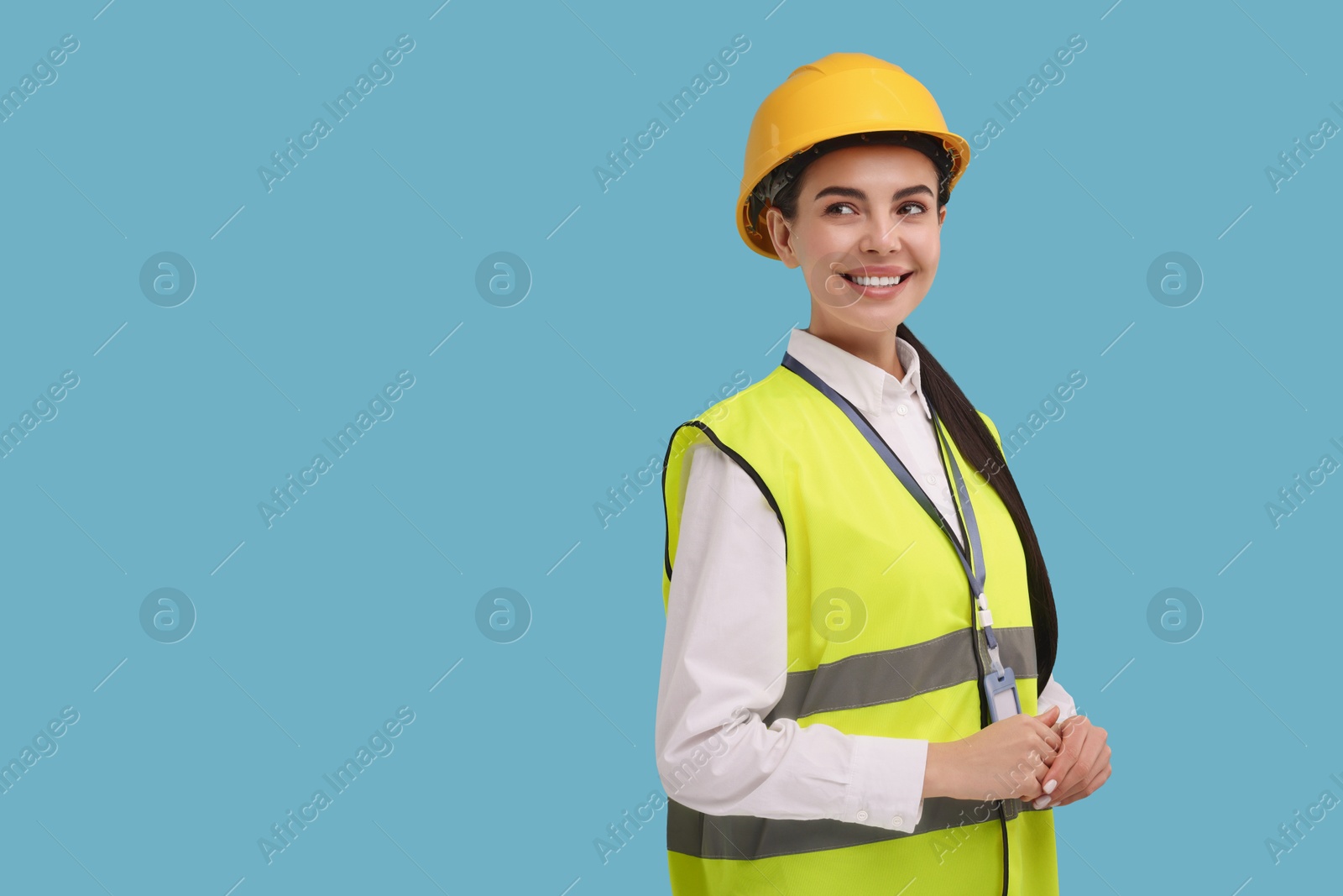 Photo of Engineer with hard hat and badge on light blue background, space for text