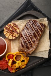 Photo of Delicious grilled beef steak with spices and tomato sauce on dark gray table, top view