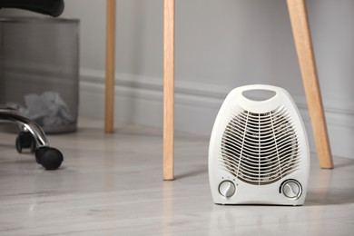 White electric fan heater on floor at home. Space for text