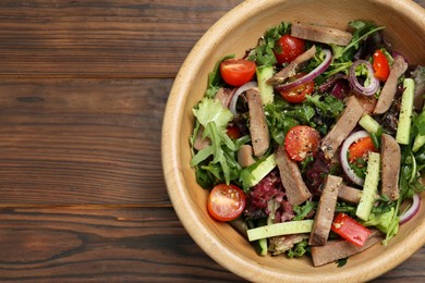 Delicious salad with beef tongue and vegetables on wooden table, top view. Space for text