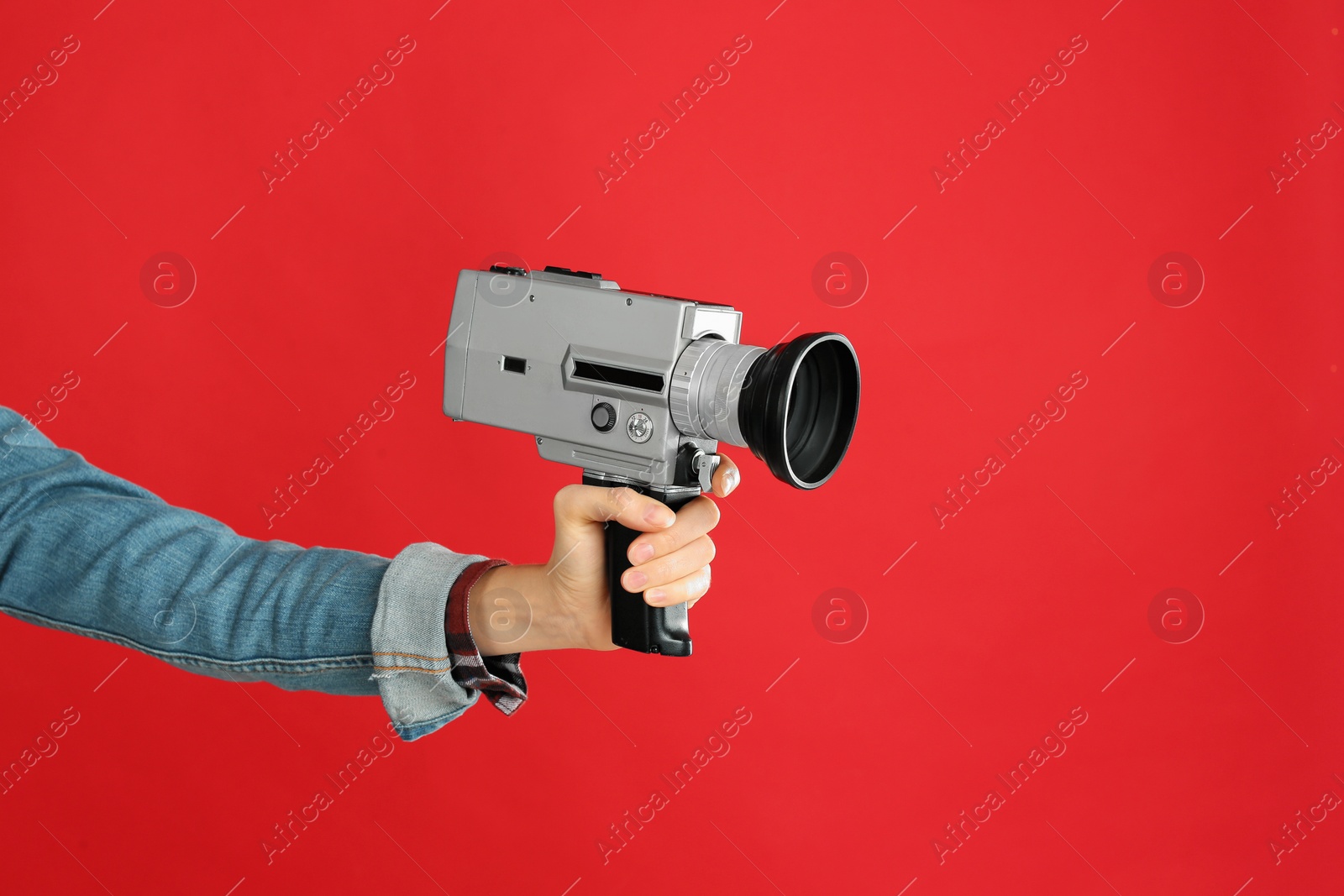Photo of Woman with vintage video camera on red background, closeup of hand