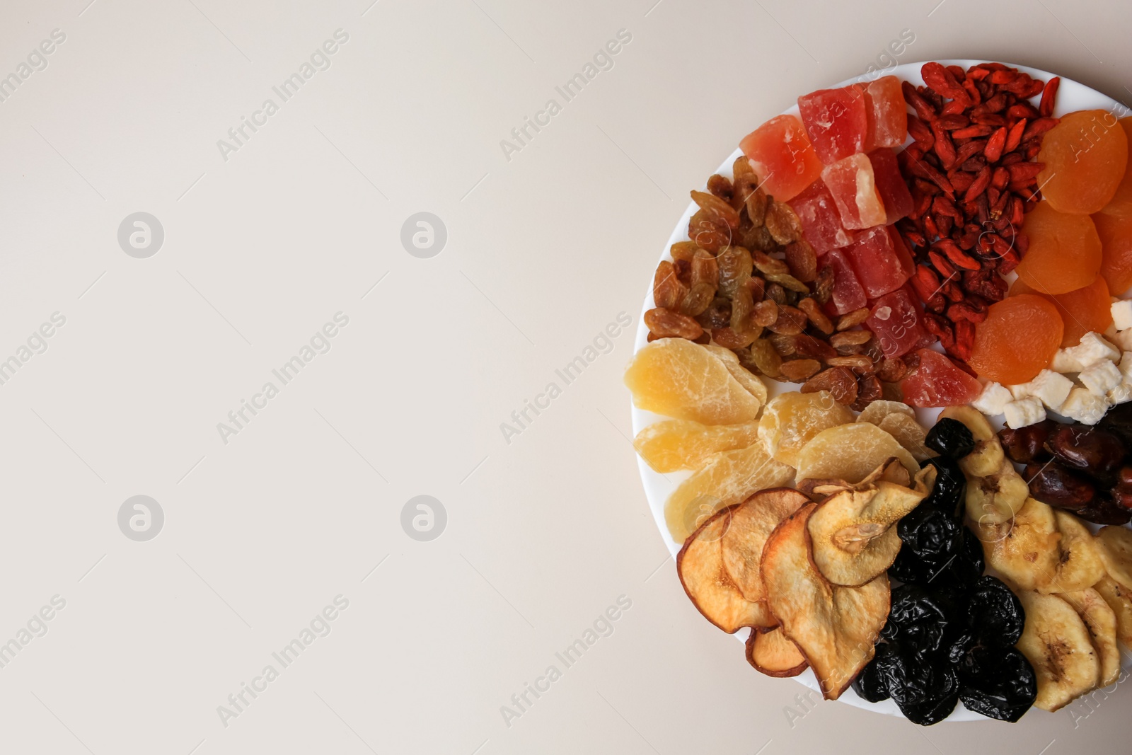 Photo of Plate with different dried fruits on white background, top view. Space for text