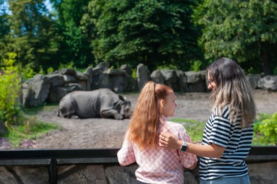 Photo of Woman with her daughter looking at wild rhinoceros in zoo