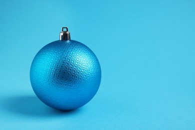 Photo of One Christmas ball on light blue background. Space for text